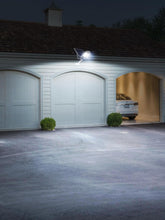 Garage with a car inside, illuminated by a security light on a house exterior.